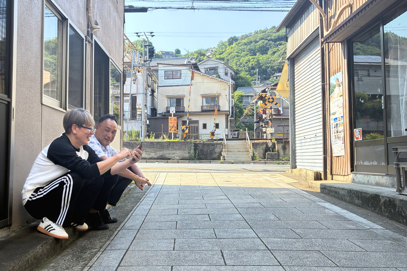 路地に腰を下ろす島田さんと山本さん